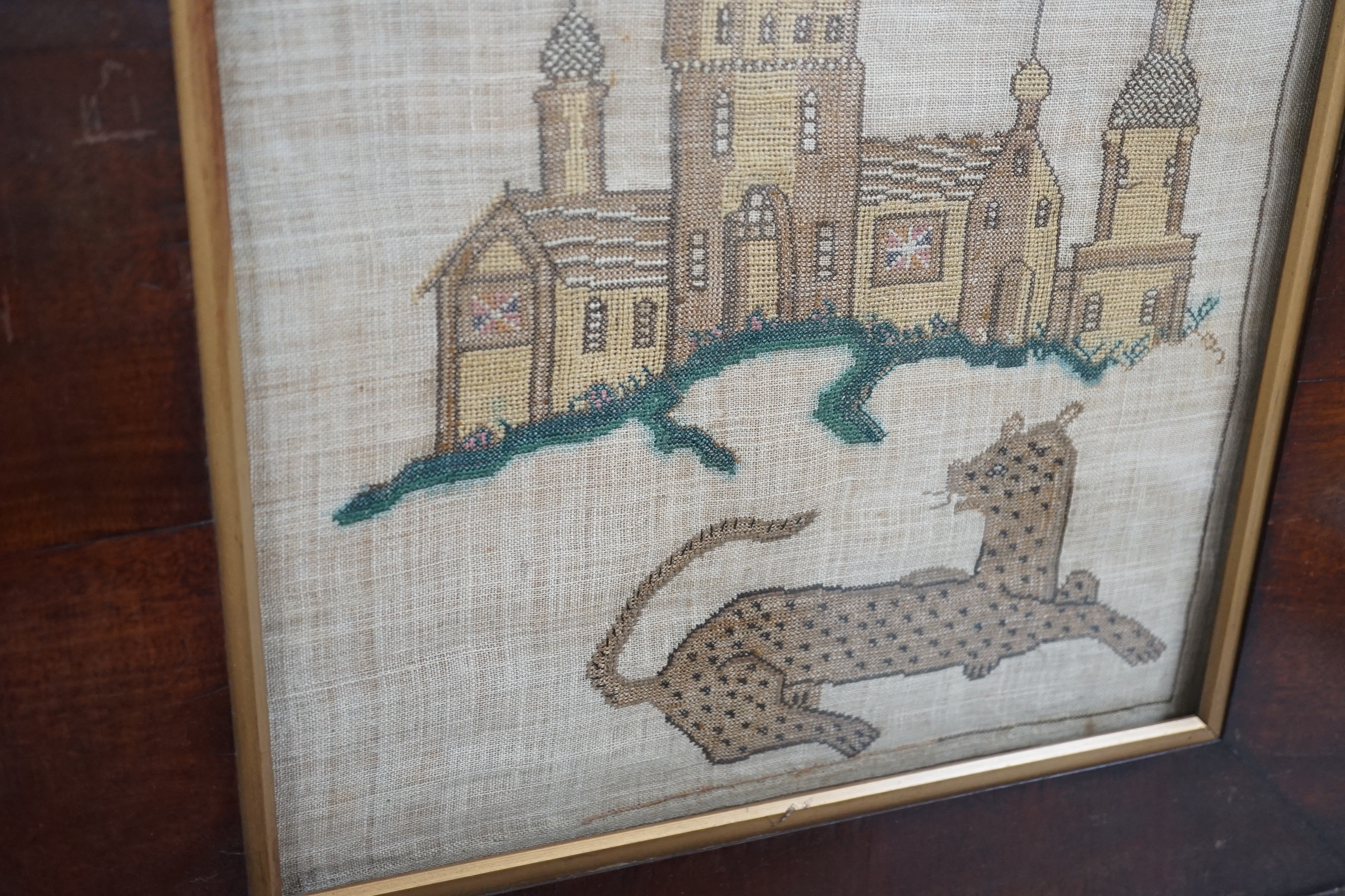 A late Georgian needlework of a leopard and castle , together with a turned wooden framed convex mirror and a similar ebony and gilt framed convex mirror, needlework 31 cms x 36 cms